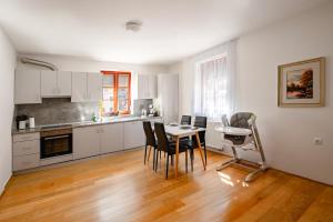 Apartmaji Pr' Kopavank في رادتشة: مطبخ مع دواليب بيضاء وطاولة وكراسي