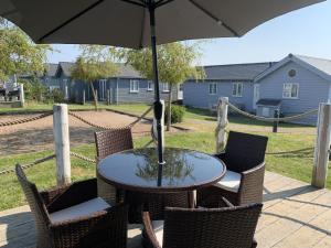 a table and chairs with an umbrella on a patio at Blue Anchor Retreat at The Bay Filey, sleeps 4, 2 dogs welcome for free too in Filey