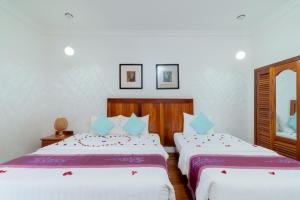 a bedroom with two beds and a mirror at Asanak D'Angkor Boutique Hotel in Siem Reap