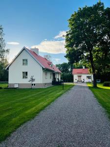 Prästgården في Norberg: بيت ابيض فيه شجرة وممر