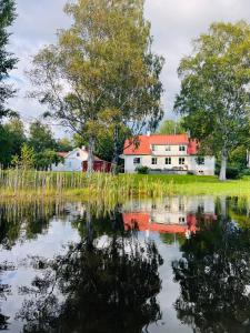 Prästgården في Norberg: بيت ابيض بسقف احمر انعكس في البركه