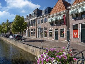 a street with buildings next to a river with flowers at Modern renovated apartment in the heart of Sneek in Sneek