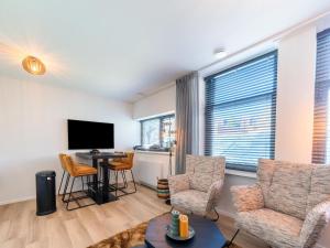a living room with a tv and chairs and a table at Modern renovated apartment in the heart of Sneek in Sneek