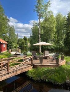 una terraza de madera con sillas y una sombrilla en un río en Prästgården en Norberg
