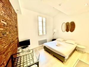 a white room with a bed and a tv at Le Caboteur - Studio proche Place de la Daurade in Toulouse