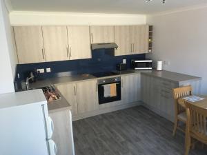 cocina con armarios de madera y horno con fogones en 2 Bedroom Townhouse on NC500, Wick, Highland, en Wick