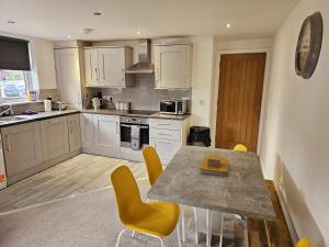 a kitchen with a table and yellow chairs at Homebird Property - Epsom Apartment in Harrogate