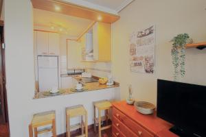 una cucina con lavandino e bancone con sgabelli di Acacios en La Concha a Suances