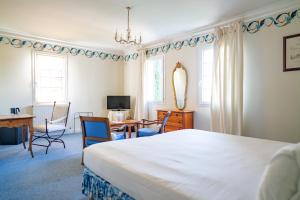 a bedroom with a white bed and a desk and chairs at Hôtel de Margaux in Margaux