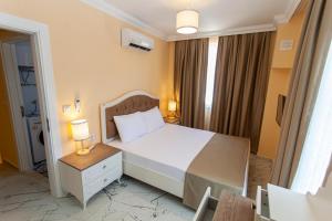 um quarto com uma cama branca e uma mesa de cabeceira com 2 candeeiros em Yellow Villa em Muğla