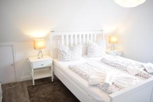 biała sypialnia z 2 łóżkami i 2 lampami w obiekcie Ocean Way House w mieście Haffkrug