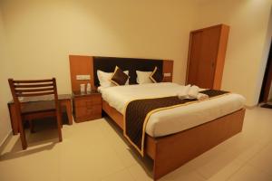a bedroom with a bed with a chair and a desk at Hotel Ashok Palace in Karūr
