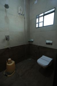a bathroom with a toilet and a window at Hotel Ashok Palace in Karūr