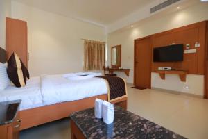a hotel room with a bed and a flat screen tv at Hotel Ashok Palace in Karūr +33 photos