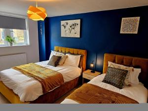 Homebird Property - Epsom Apartment في هاروغايت: غرفة نوم بسريرين وجدار ازرق
