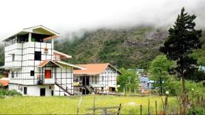 una casa en un campo frente a una montaña en Keerong Cottages Lachung, en Lachung
