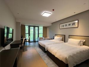 um quarto de hotel com duas camas e uma secretária em Ramada by Wyndham Taizhou West em Taizhou