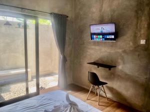 a bedroom with a bed and a desk and a television at The Backyard Villas in Tabanan