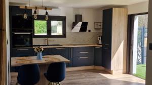 een keuken met blauwe kasten en een tafel en stoelen bij Cocooning LE MUGEL aux portes des calanques de Cassis & SPA in Carnoux