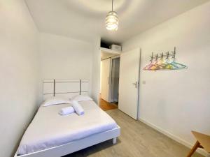 a bedroom with a bed with white sheets and purple pillows at La Garonne - T3 avec parking privé in Toulouse