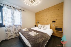 1 dormitorio con 1 cama grande y pared de madera en Chez Stella 3 chambres neuf plein centre en Huez