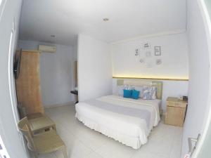 a white bedroom with a bed and a chair at RedDoorz near Jalan Gatot Subroto Barat Denpasar in Kerobokan