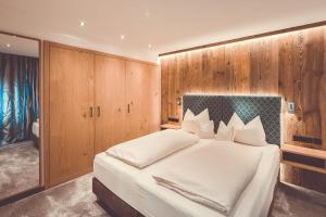 a bedroom with a large white bed with wooden walls at Hotel Alpenkönig in Oberstaufen