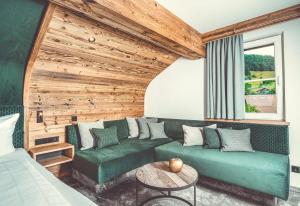 a living room with a green couch and a wooden wall at Hotel Alpenkönig in Oberstaufen