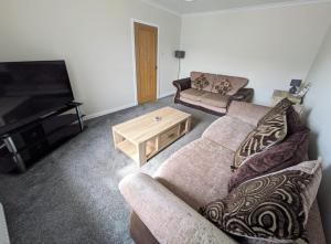 a living room with a couch and a flat screen tv at 2 Bedroom Townhouse on NC500, Wick, Highland in Wick