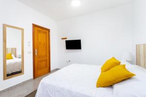 ein Schlafzimmer mit einem Bett mit gelben Kissen und einem Spiegel in der Unterkunft EDEN RENTALS 105 Surfy Stylish Bed&Coffee Room in Granadilla de Abona
