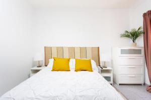una camera da letto con un letto bianco con cuscini gialli di EDEN RENTALS 105 Surfy Stylish Bed&Coffee Room a Granadilla de Abona