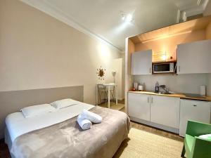 a bedroom with a large white bed and a kitchen at Les Capitole I - Studio avec climatisation in Toulouse