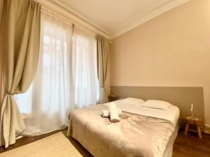 a bedroom with a bed with white sheets and a window at Les Capitole I - Studio avec climatisation in Toulouse