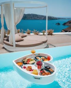 ein Tablett mit Speisen am Rande eines Pools in der Unterkunft The Saint Hotel in Oia