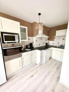 a kitchen with white cabinets and a microwave at Brise de Thau in Balaruc-les-Bains