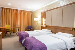 a hotel room with three beds and a desk at Reikartz Sky Almaty in Almaty
