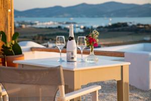 - une table avec 2 bouteilles et 2 verres de vin dans l'établissement Anthemion Paros - Villas & Suites, à Agia Irini Paros