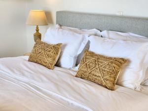 a white bed with white pillows and a lamp at Anthemion Paros - Villas & Suites in Agia Irini Paros