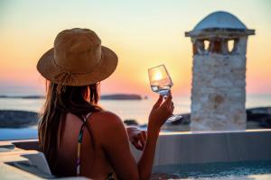 kobieta w kapeluszu trzymająca kieliszek wina w obiekcie Anthemion Paros - Villas & Suites w mieście Agia Irini Paros