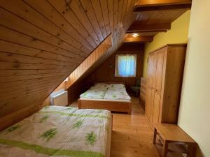 two beds in a room with a wooden ceiling at Drevenica Čakanka a Nezábudka in Terchová