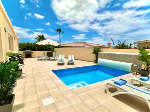 una piscina con 2 tumbonas y un patio en Villa Casa Sol, en Chayofa