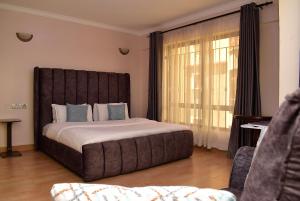 um quarto com uma cama grande e uma janela grande em RAVIC HOMES NAKURU em Nakuru