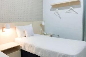 um quarto de hotel com uma cama branca e uma janela em Rumah Teuku Umar Mitra RedDoorz em Kedongdong