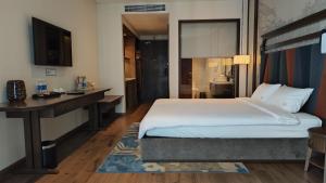 a bedroom with a bed and a desk and a television at Apec Mandala Wyndham Phan Thiet - Mui Ne in Ấp Thiẹn Ái