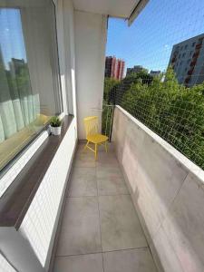 una sedia gialla seduta su un balcone con finestra di Gallusa Apartament a Katowice
