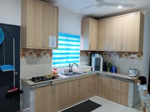 a small child standing in a kitchen with wooden cabinets at Teratak Amani Hometay in Tawau