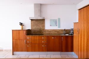 una cocina con armarios de madera y fregadero en La Belle Ferme en Cottens