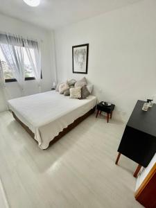 a white bedroom with a large bed and a piano at Vista Panorâmica com piscina in Porto Alegre