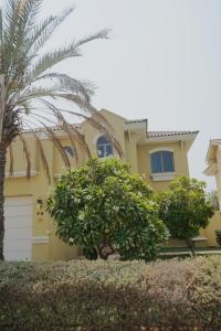 a yellow house with a palm tree in front of it at The Atlantis Hotel View, Palm Family Villa, With Private Beach and Pool, BBQ, Front F in Dubai