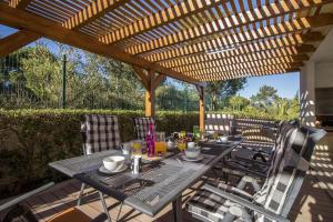 a patio with a table and chairs under a wooden pergola at Villa Joy in Olhos de Água